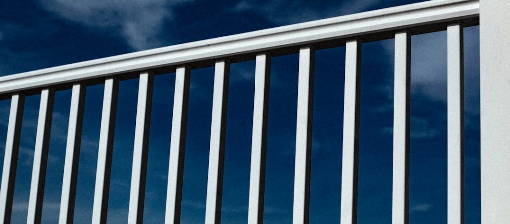 white-and-blue-striped-metal-railings-under-blue-sky-kpiml0hbwfi